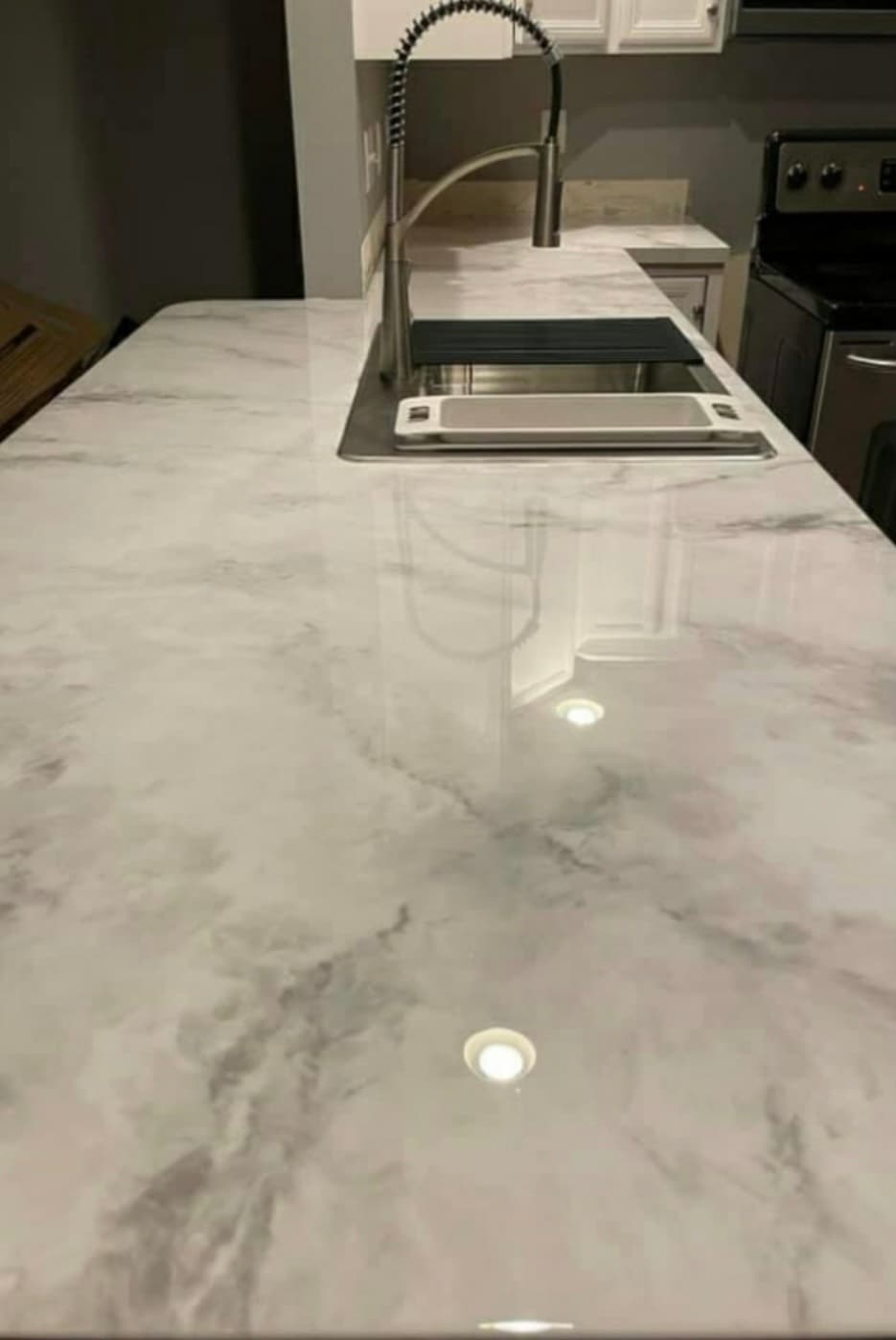 High-gloss white marble-patterned kitchen countertop with a modern pull-down faucet and stainless steel sink.